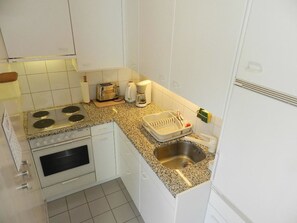 Cocina compacta con estufa, horno, pileta y cafetera.