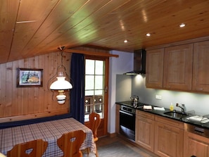 A wooden interior with a dining table, chairs, a stove, and cabinets. - Hornflue (Baumann) Appartement/Fewo, Dusche oder Bad, WC 4-Bettwohnung by Interhome (Gstaad)
