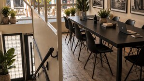 A modern conference room with a long table, black chairs, and potted plants.