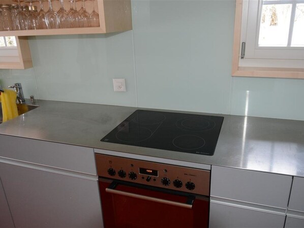 Una cucina con un piano di lavoro in acciaio inossidabile, un fornello nero e un forno rosso.