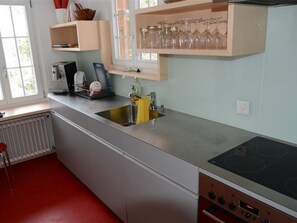 A kitchen with a stainless steel countertop, a built-in oven, and a window above the sink. - Les Erables, Chalet Appartement/Fewo, Dusche oder Bad, WC 7-Bettwohnung by Interhome (Gstaad)