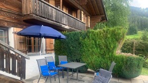 Un edificio in legno con un balcone, un tavolo con sedie e una poltrona da relax.