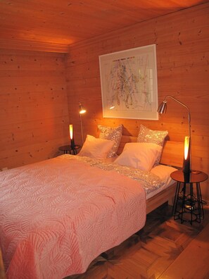 Ein gemütlicher Holzraum mit einem Bett, zwei Nachttischlampen und einer Karte an der Wand.