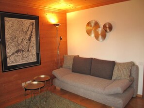A cozy living room with a sofa, a framed abstract artwork, a floor lamp, and decorative wall art.
