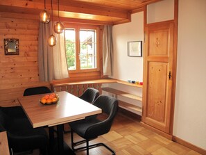 A wooden interior with a dining table, chairs, a window with curtains, and a door. - Les Hivernants (EG links) Appartement/Fewo, Dusche oder Bad, WC, 1 Schlafraum by Interhome (Gstaad)