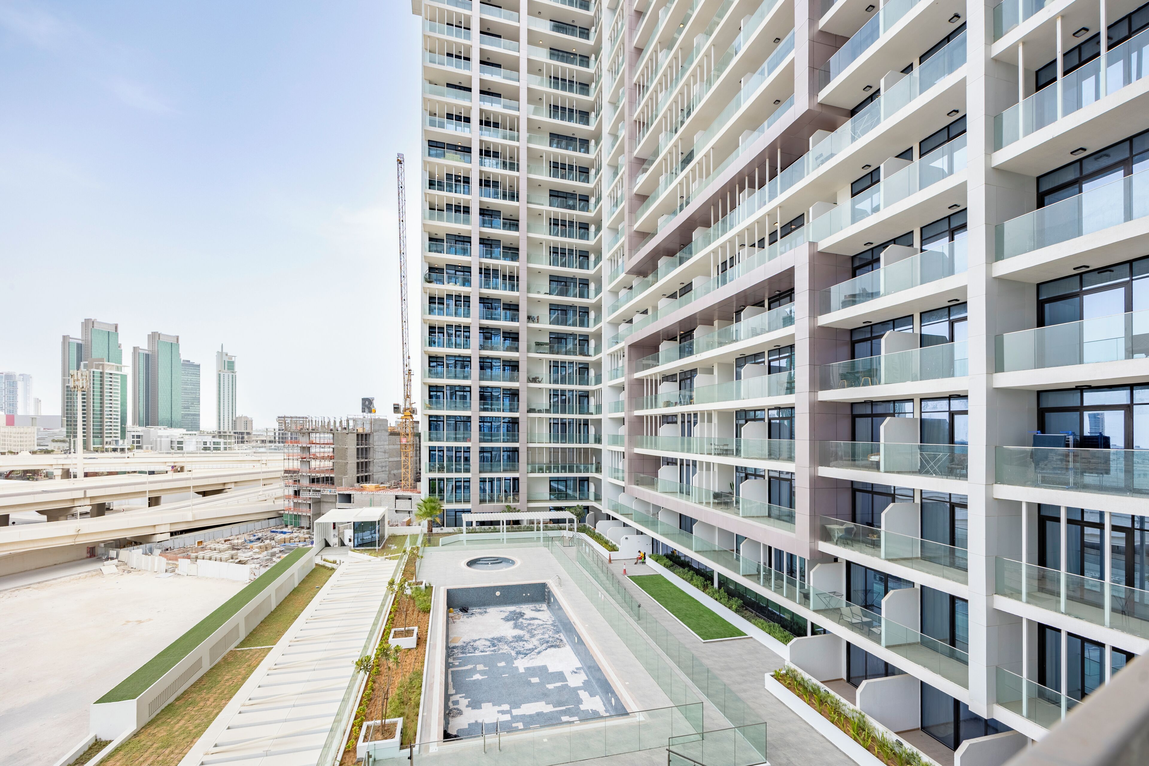 A modern high-rise building with multiple balconies, a rooftop garden, and a view of the city skyline.