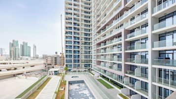 A modern high-rise building with multiple balconies, a rooftop garden, and a view of the city skyline.