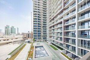 A modern high-rise building with multiple balconies, a rooftop garden, and a view of the city skyline. - Bloomfields 1BR in Al Maryah Vista  (Abu Dhabi)