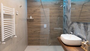Une salle de bain moderne équipée d’un bidet, d’un lavabo, d’une douche et d’un meuble-lavabo.