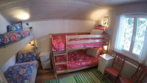Camera con letto a castello, una finestra, una sedia e un termosifone.