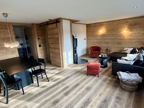A modern living space with a dining area, a sofa set, a red armchair, and a fireplace. - Ariel Appartement/Fewo, Dusche oder Bad, WC 8-Bettwohnung by Interhome (Gstaad)