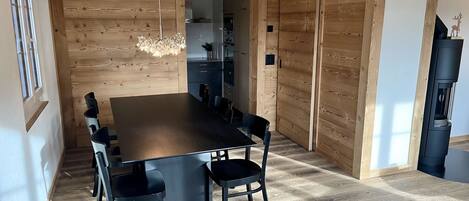 A modern dining area with a wooden wall, a black dining table, and chairs.