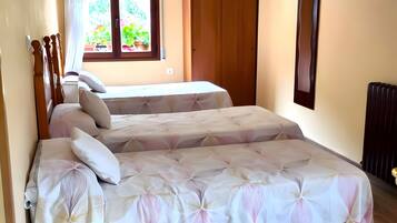 Un dormitorio con dos camas, una ventana con cortinas, una lámpara colgante y un radiador.