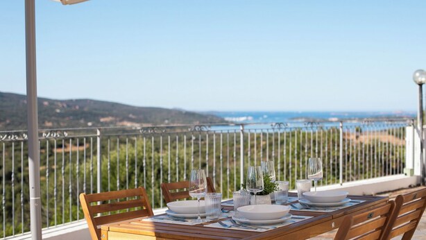 A table set outdoors with a view of the sea and hills. - Casa del Miso by Wonderful Italy (Sardegna)