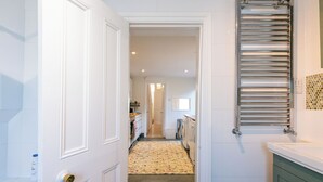 Een gang die uitkomt bij een badkamer met een handdoekhouder en een toilet.