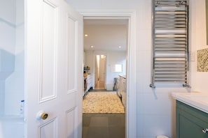 A hallway leading to a bathroom with a towel rack and a toilet. - Charming Garden Home in Brixton (Greater London)