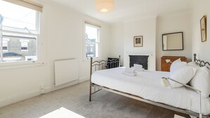 Een slaapkamer met een enkel bed, een radiator, een raam en een open haard.