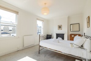 A bedroom with a single bed, a radiator, a window, and a fireplace. - Charming Garden Home in Brixton (Greater London)