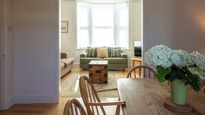 Een woonkamer met een bank, een salontafel en een houten eettafel.