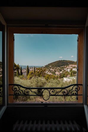 A balcony with a wrought iron railing overlooking a residential area with houses and trees.