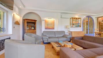Een woonkamer met een grijze bank, een houten salontafel en een kast met drinkglazen.