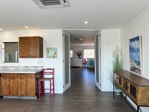 A modern kitchen with wooden cabinets, a red chair, and a dining area with a wooden table and bench.