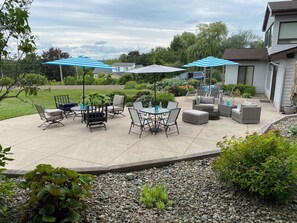 A patio with outdoor furniture, umbrellas, and a landscaped garden.