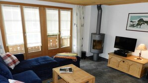 Uma sala de estar aconchegante com sofá, televisão, armário de madeira e lareira.