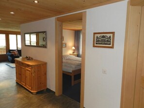 Une chambre d’hôtel avec une armoire en bois, un lit, une table de chevet, une lampe et un tableau encadré au mur.