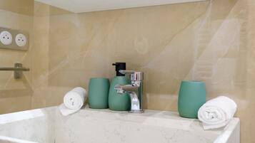 Een badkamer met een bad, een kraan en twee groene bekers op het aanrecht.
