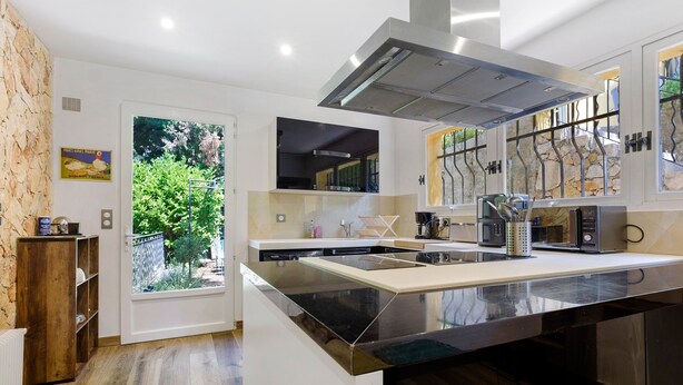 A modern kitchen with a large island, built-in appliances, and a view through the window. - Lavender Room 18 m², Air-Conditioned, Garden Level, Shared Lounge, Kitchen & Garden (Grasse)