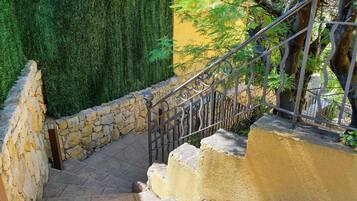 Un escalier en pierre avec une rampe métallique menant à un mur jaune.