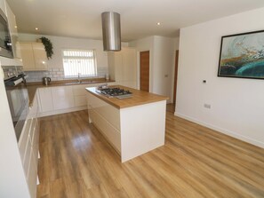 Una cocina moderna con una isla central, electrodomésticos de acero inoxidable y suelo de madera.