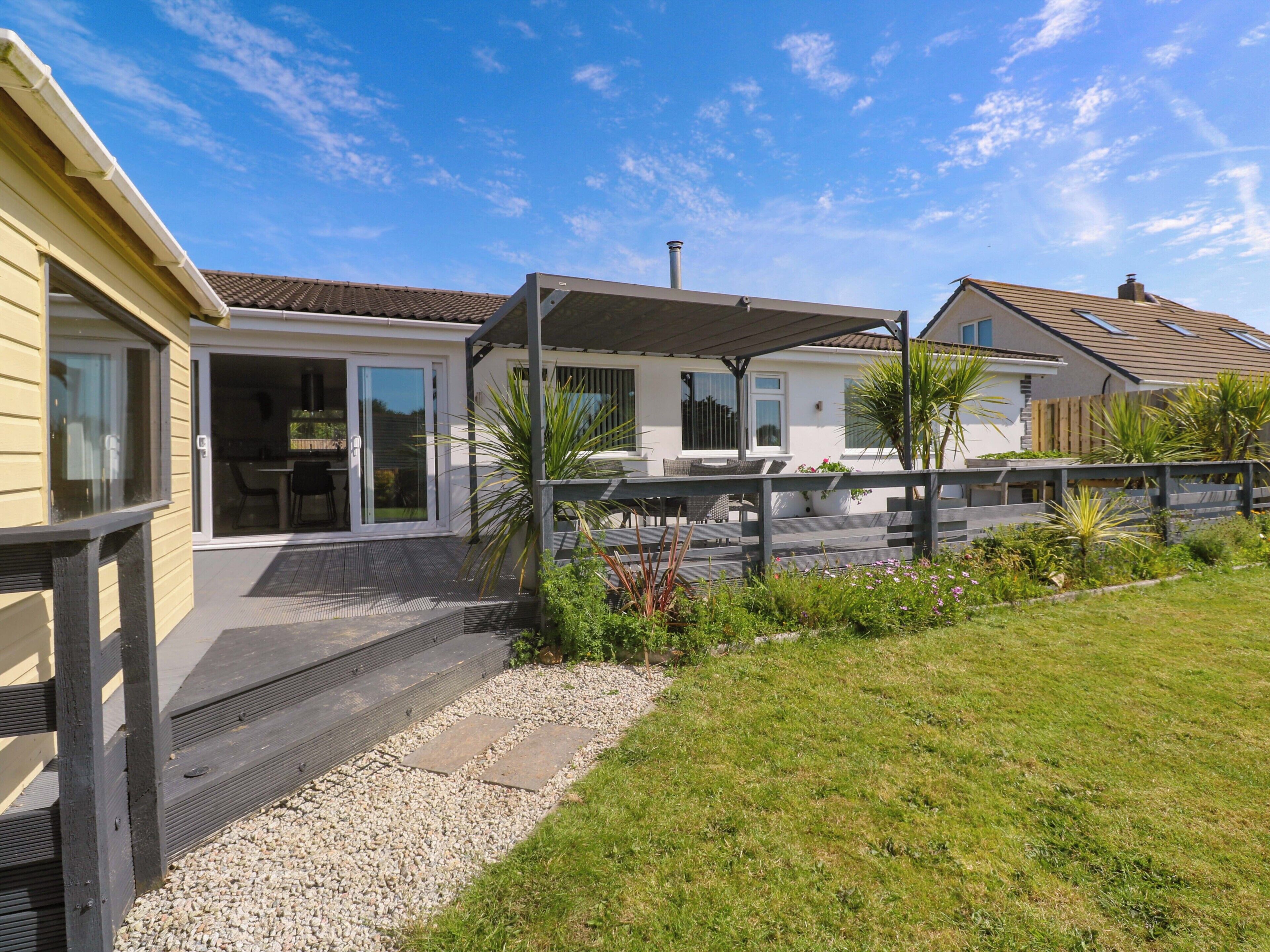 Ein Wohnhaus mit Terrasse, Sitzgelegenheiten im Freien und einem Garten.