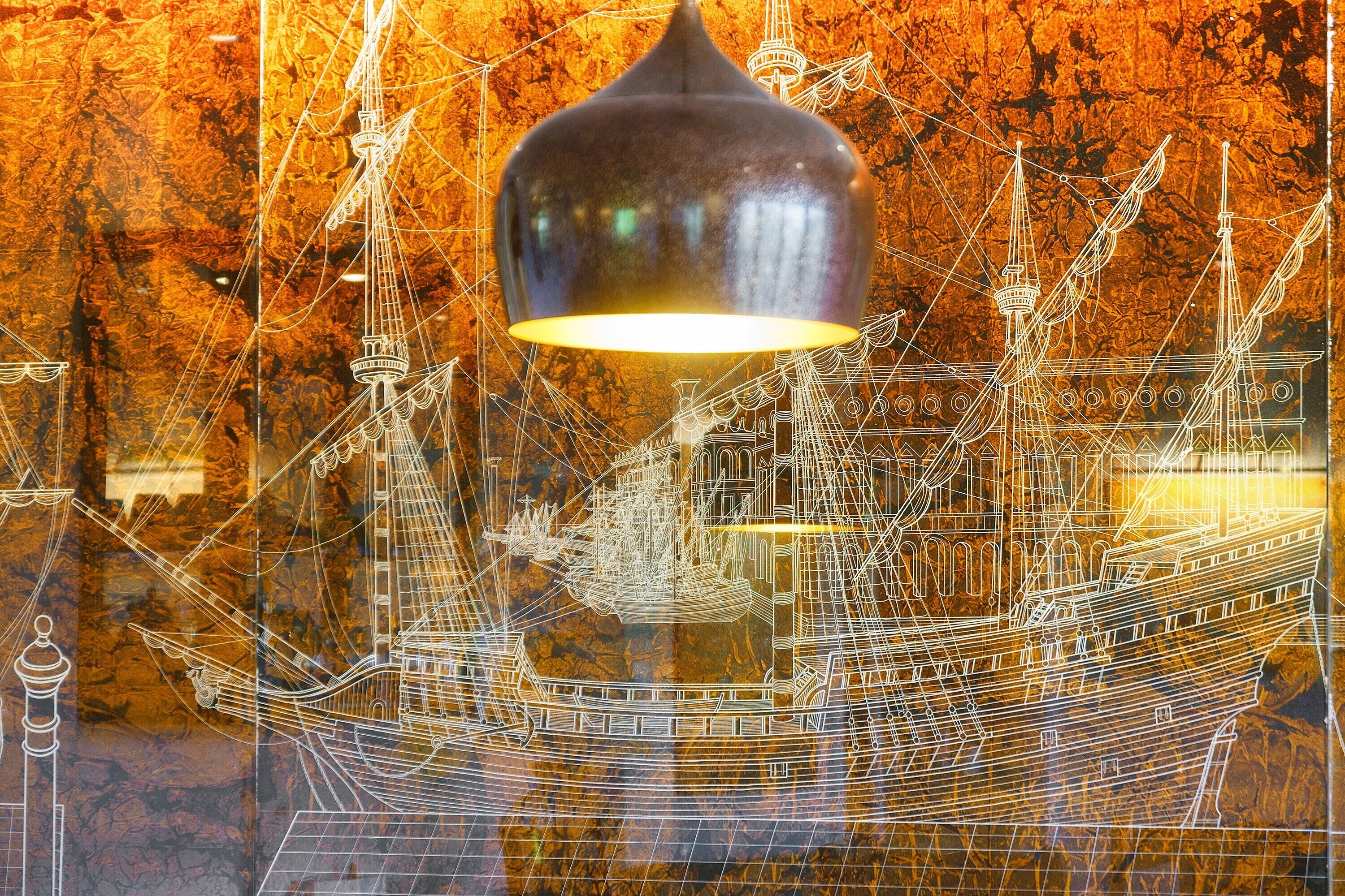 A chandelier with a reflective surface and a complex background of architectural drawings.