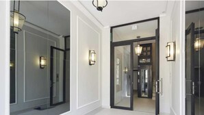 A hallway with a glass door leading to a room, a light fixture on the wall, and a mirror reflecting the interior. - EXCEPTIONAL 200 M² PENTHOUSE, JUST A ONE-MINUTE WALK FROM THE ICONIC CROISETTE (Cannes)