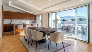 A modern kitchen with marble countertops, a dining area with a round table and chairs, and a balcony with outdoor seating. - EXCEPTIONAL 200 M² PENTHOUSE, JUST A ONE-MINUTE WALK FROM THE ICONIC CROISETTE (Cannes)