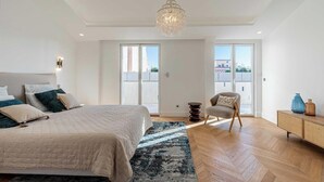 A bedroom with a large bed, a chair, a small table, and a chandelier. - EXCEPTIONAL 200 M² PENTHOUSE, JUST A ONE-MINUTE WALK FROM THE ICONIC CROISETTE (Cannes)