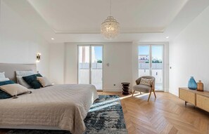 A bedroom with a large bed, a chair, a small table, and a chandelier. - EXCEPTIONAL 200 M² PENTHOUSE, JUST A ONE-MINUTE WALK FROM THE ICONIC CROISETTE (Cannes)