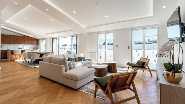 A spacious living area with a sofa, chairs, a dining table, and a kitchen in the background. - EXCEPTIONAL 200 M² PENTHOUSE, JUST A ONE-MINUTE WALK FROM THE ICONIC CROISETTE (Cannes)