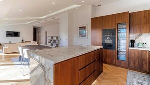A modern kitchen with wooden cabinets, a marble countertop, and built-in appliances. - EXCEPTIONAL 200 M² PENTHOUSE, JUST A ONE-MINUTE WALK FROM THE ICONIC CROISETTE (Cannes)