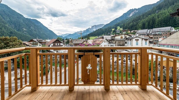 A wooden balcony with a view of a mountain town and a clear sky. - Elbetina Penthouse, in the center of Campitello di Fassa with a panoramic view (Campitello di Fassa)