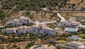Un resort costero con edificios de piedra, una piscina y un camino sinuoso.