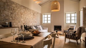 A spacious living area with a stone wall, a fireplace, and a dining table set with wine glasses and a fruit bowl.