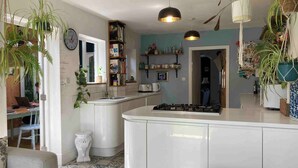 A kitchen with a central island, a dining area with a chair, and a bookshelf. - Cambridge Center - Riverside - On a no-through road leading to the River Cam (Cambridge)