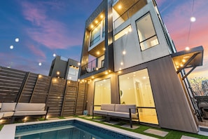 A modern two-story house with a swimming pool, outdoor seating, and string lights. - 360 City Views+Pool, Hot tub, Sauna, Rooftop (Dallas)