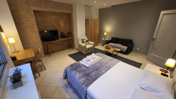 Een hotelkamer met een bed, een televisie, een bank, een klein tafeltje en een bureau.