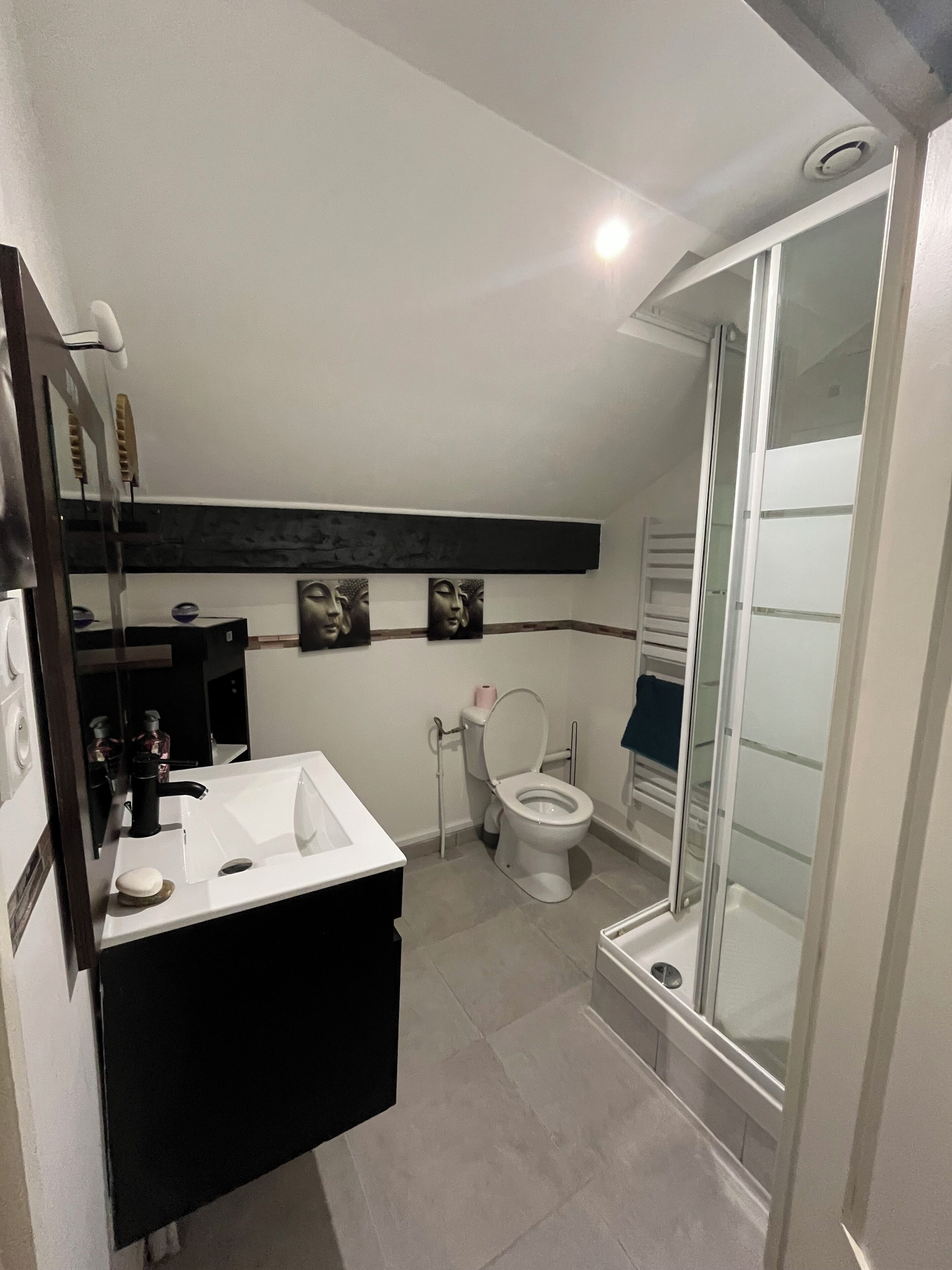 Een badkamer met een wit wastafelmeubel, toilet, glazen douchecabine en spiegel.