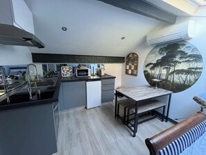 Een moderne keuken met een eethoek, een ingebouwde magnetron en een groot raam met uitzicht op bomen.