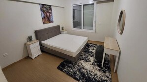 Un dormitorio con cama, mesita de noche y ventana con persianas.